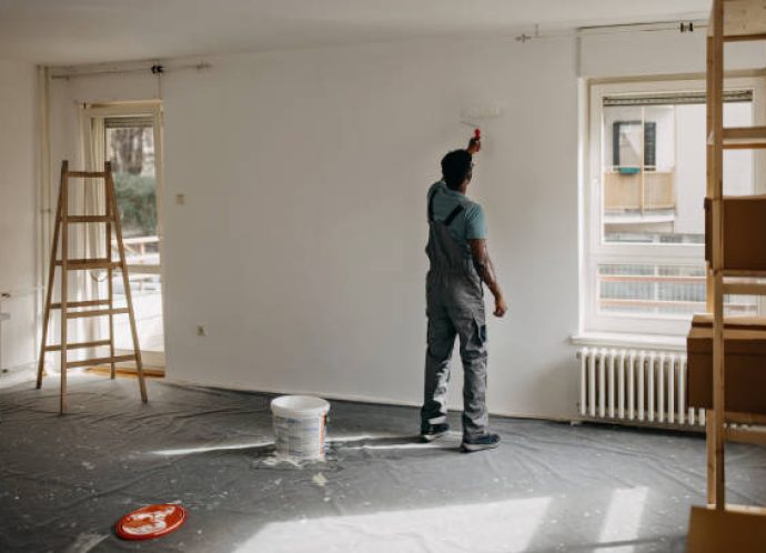 African-American professional painter paints the wall indoors